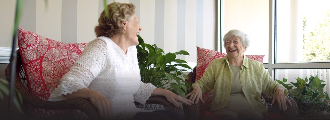 Two residents sharing a laugh in a cozy lounge area