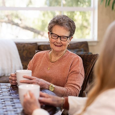 A senior resident enjoying tea in a common area