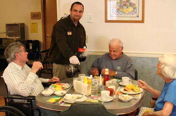 Residents enjoying breakfast with staff in a dining area