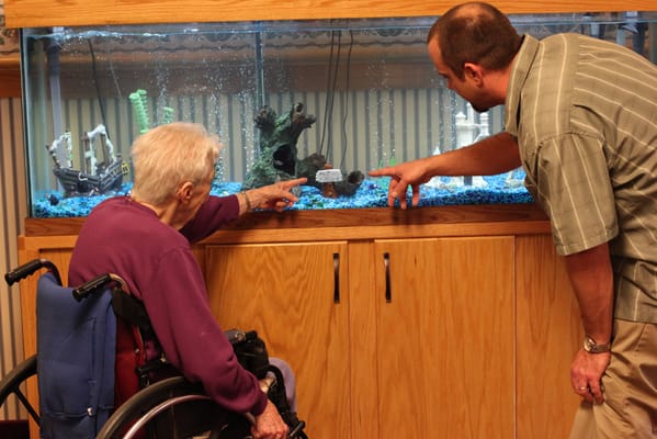 Resident and staff member engaging by an aquarium