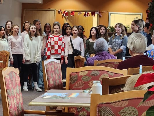 A group of children singing for residents in a common area