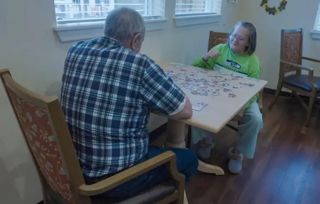 Two residents assembling a puzzle in a cozy interior
