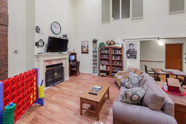 Common area with seating and bookshelf in a senior living facility
