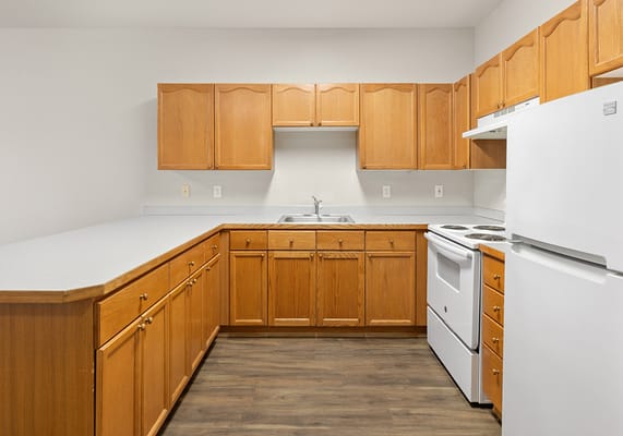 Bright kitchen area with wooden cabinets and appliances