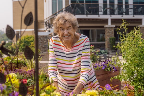 A resident smiling while gardening in outdoor flowers