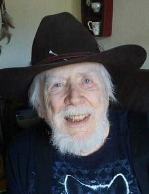 Elderly man smiling wearing a hat indoors