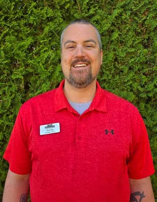 Staff member smiling in front of greenery