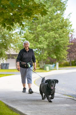 Senior resident walking a dog in a green outdoor area