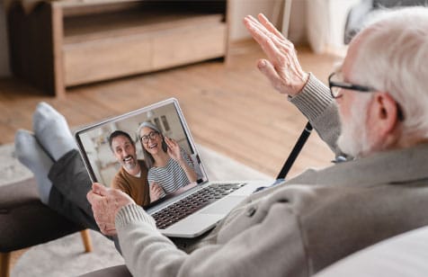 An elderly man video chatting with family on a laptop