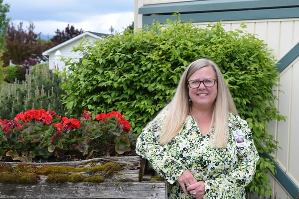 Staff member posing in front of flower beds