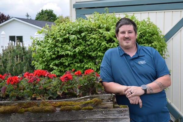 Staff member posing near a flower bed