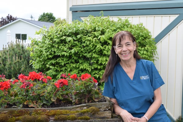 A staff member smiling in a garden with flowers