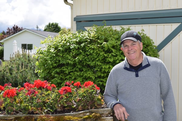 Senior resident smiling by a flower garden
