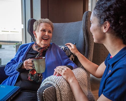 Happy resident and staff member in a cozy lounge area