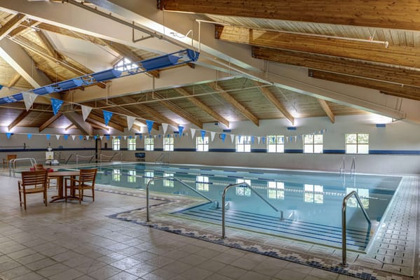 Indoor swimming pool with wooden beams and seating area