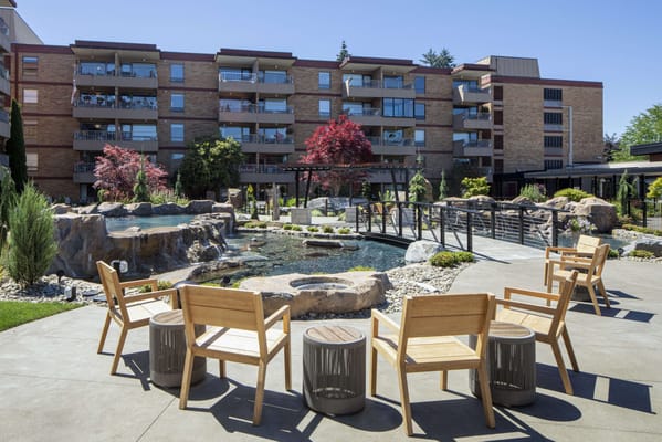 Outdoor seating area with a pond and building in the background