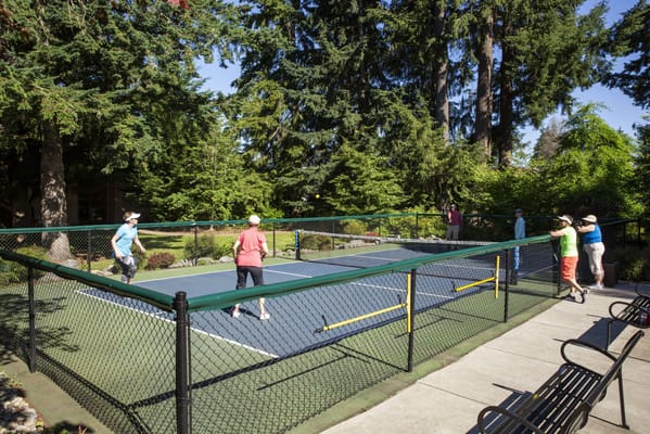 Residents enjoying tennis in a green outdoor area