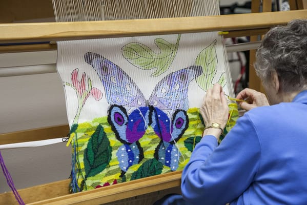 Resident weaving a colorful butterfly tapestry
