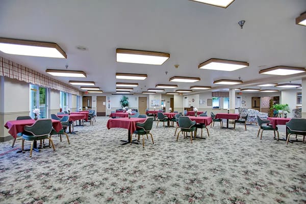 Bright common area with tables and chairs, floral carpet