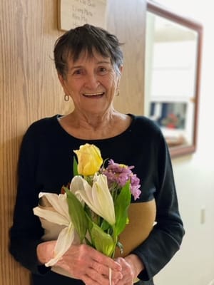 Resident holding a bouquet of flowers in a hallway