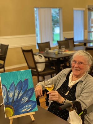 Resident painting with a drink in hand during an activity