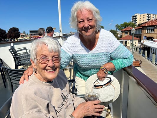 Two smiling residents enjoying the outdoors on a boat deck