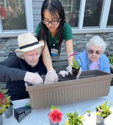 Residents planting flowers with staff assistance