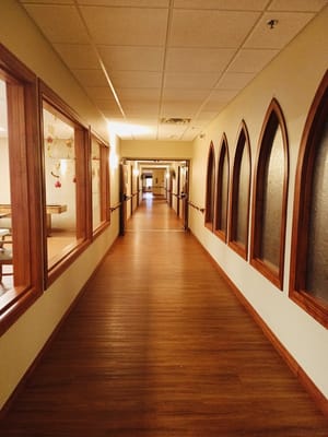 A well-lit hallway with wooden details in a senior care facility