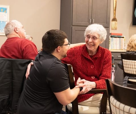 An elderly woman smiling and talking with a staff member