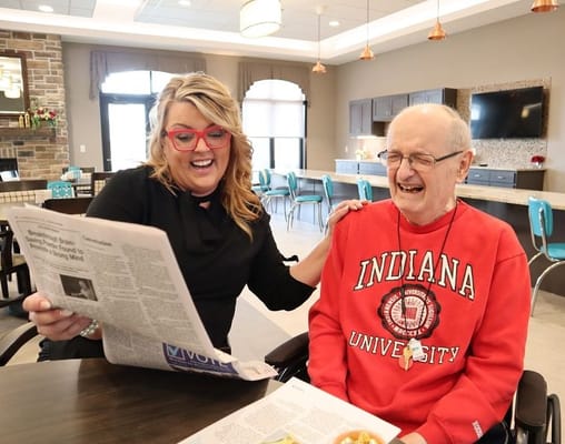 Staff member and resident reading a newspaper together
