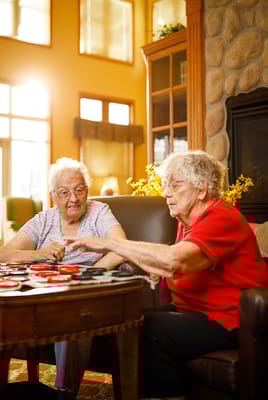 Two residents playing checkers in a bright common area