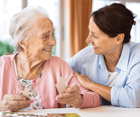 A caregiver and resident enjoying a puzzle together