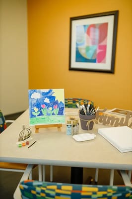 Art supplies and a painting on a table in an activity room