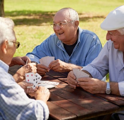 Residents playing cards outdoors in a sunny garden