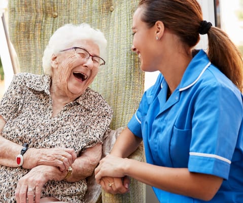 A caregiver laughing with a resident in a cozy setting