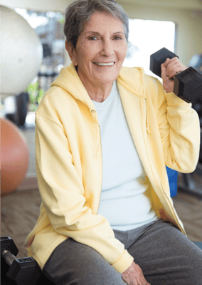 Senior resident exercising with weights in a fitness room