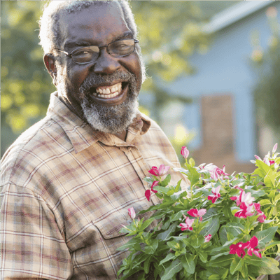 Resident smiling while holding flowers in a garden