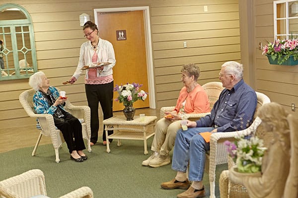 A staff member serving snacks to residents in a common area