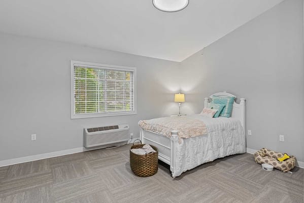 Bright, cozy resident room with a bed and lamp