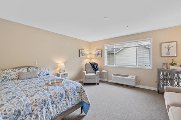 Bright, welcoming resident room with a bed and seating area