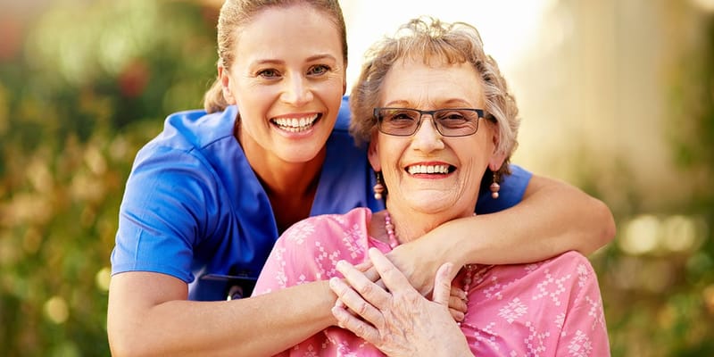 Smiling caregiver with a resident outdoors