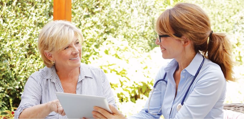 A doctor and resident sharing a tablet in a garden