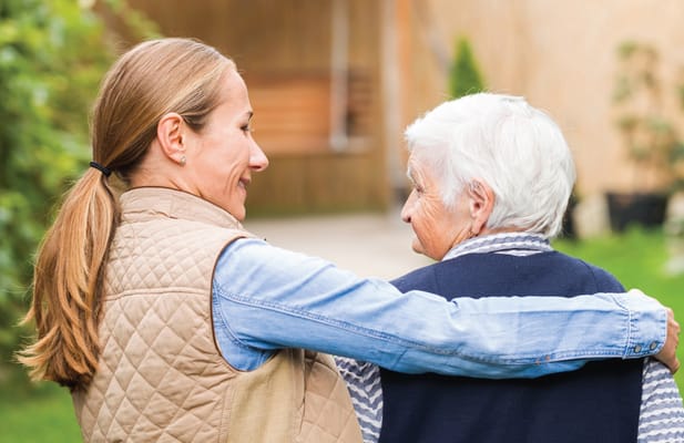A staff member embracing a senior resident outdoors
