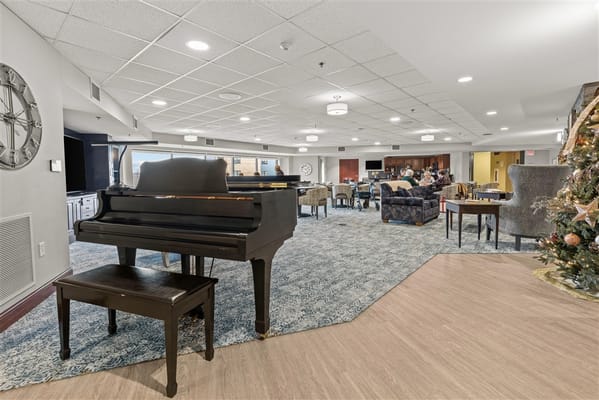 Common area with residents socializing around a piano