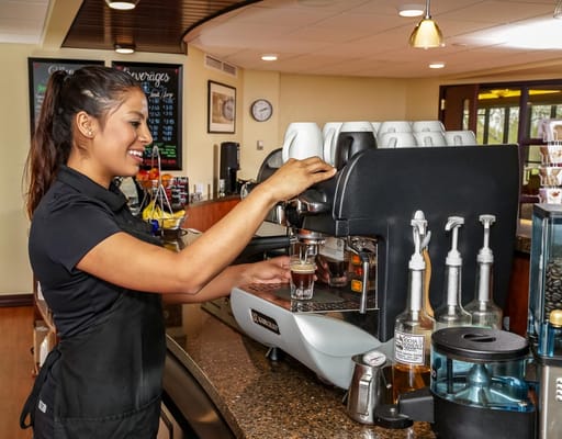 Staff member preparing coffee at a facility café