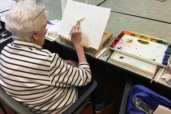Resident painting at a table during an art activity