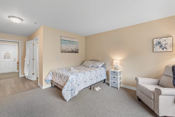 A cozy resident room with a bed and armchair