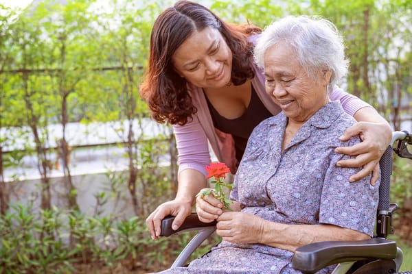 A caregiver with an elderly woman in a garden