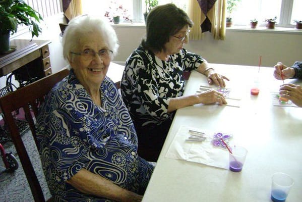 Two residents participating in a colorful craft activity