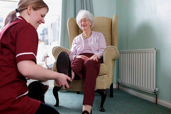 Staff assisting a resident in a cozy lounge area